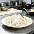 Thin slices of conch meat arranged on a white plate