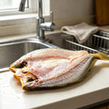 Whole yellow croaker with golden scales on a plate